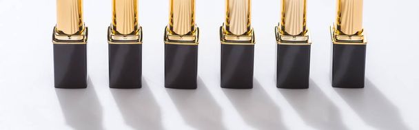 lipsticks in luxury tubes in line on white background, panoramic shot - Foto, Imagem
