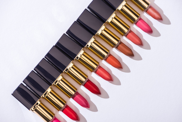 top view of assorted lipsticks in luxury tubes in line on white background - 写真・画像