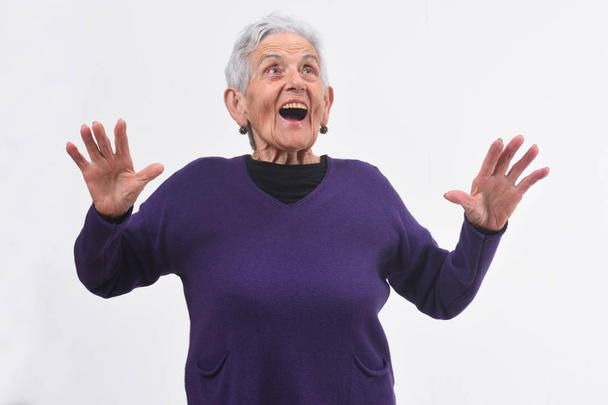 mujer mayor con una cara sorprendida y las manos levantadas en bac blanco
 - Foto, imagen