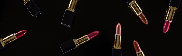 top view of assorted lipsticks in luxury tubes isolated on black, panoramic shot - 写真・画像