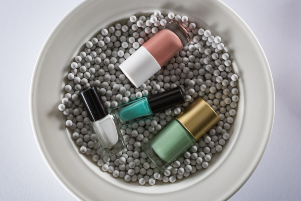 vista superior del esmalte de uñas surtido en botellas en placa con cuentas decorativas grises
 - Foto, imagen