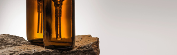 close up άποψη του διανομέα καλλυντικά μπουκάλια σε πέτρα σε λευκό φόντο με πίσω φως, πανοραμική λήψη - Φωτογραφία, εικόνα