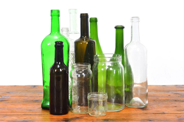 group of bottles and glass jars on a wooden table with white bac - Фото, изображение