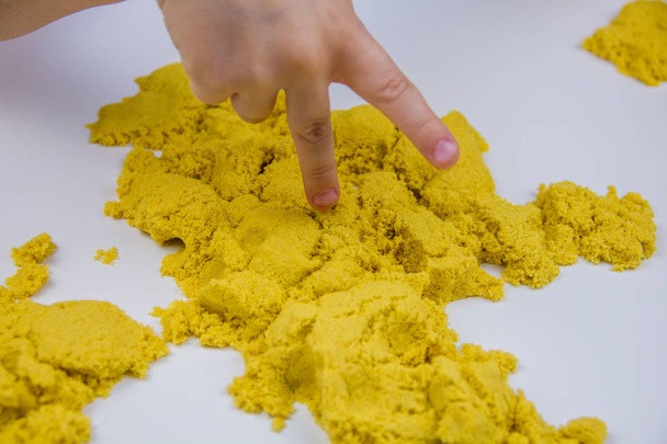 children's hands play yellow kinetic sand on a white table. Antistress - Photo, Image