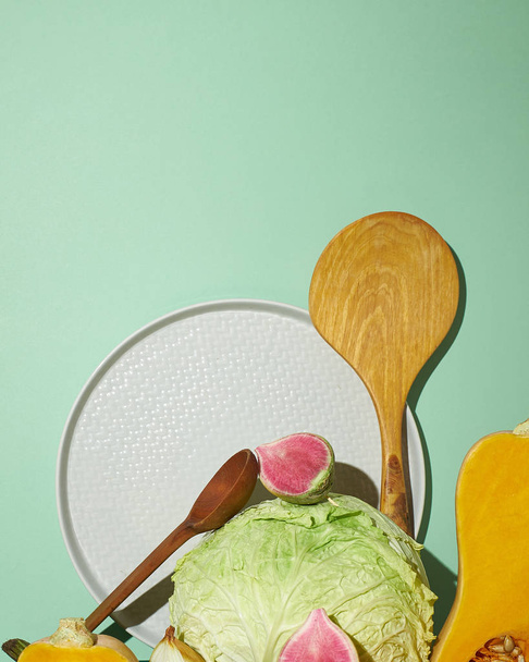 Kohl, Feigen, weißer Teller und Kochlöffel auf grünem Hintergrund - Foto, Bild