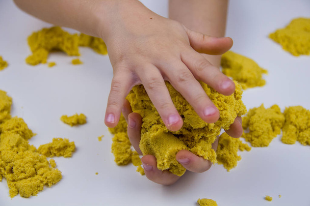 children's hands play yellow kinetic sand on a white table. Antistress - Photo, Image