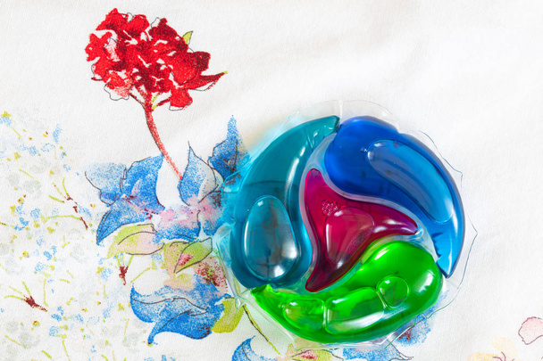 Waschmittel Hülse auf Stoff in Blumen Hintergrund - Foto, Bild