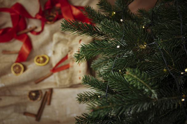 Weihnachten Hintergrund, Leinenstoff mit Dekorationen und Weihnachtsbaum mit Lichtern.   - Foto, Bild