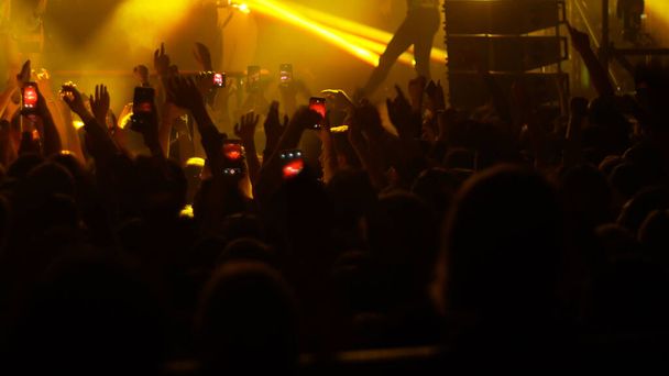 Persone energiche che ballano con le mani alzate al concerto rock - alcune persone filmano la performance al telefono
 - Foto, immagini