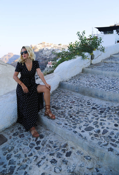 Santorini travel tourist woman on vacation in Oia. Stylish rich girl traveller posing in Oia Cyclades. - Fotoğraf, Görsel