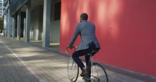 Rear view of a young Caucasian businessman on the go in the city, riding a bike in the street, slow motion - Filmagem, Vídeo