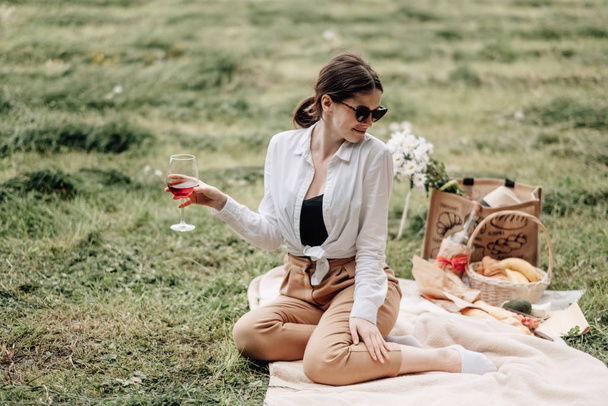 Joven chica elegante vestida con camiseta blanca divirtiéndose en el picnic, fin de semana fuera de la ciudad, concepto de vacaciones
 - Foto, imagen