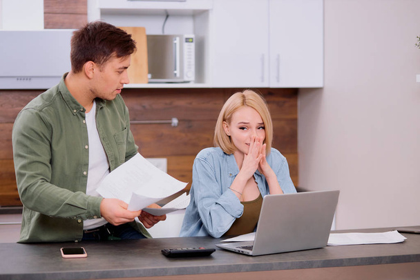 worried young couple using laptop solving financial problems at home - Foto, Bild