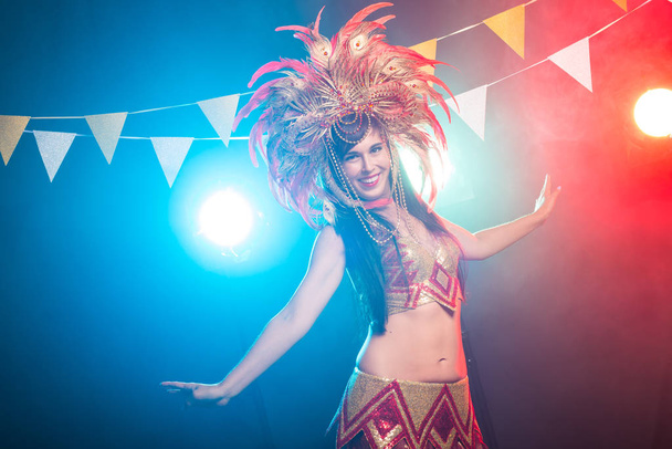 Kabarett, Tänzer und Urlaubskonzept - niedliches junges Mädchen in leuchtend buntem Karnevalskostüm auf dunklem Hintergrund - Foto, Bild