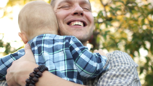 Portret szczęśliwego ojca i syna w jesiennym sadku jabłkowym. Szczęśliwa rodzina, rodzinne wakacje - Materiał filmowy, wideo