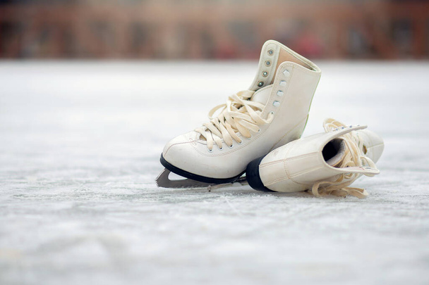 Een paar witte kunstschaatsen liggen op een open ijsbaan - Foto, afbeelding