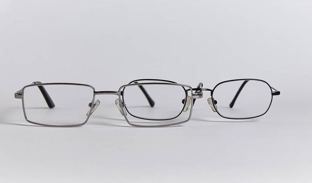 Dwie pary okularów układa się jedna po drugiej, jak dwie osoby. Szklanki zbliżenie izolowane na białym tle - Zdjęcie, obraz