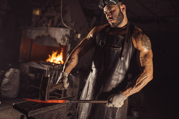 strong man working with hammer isolated in workshop - Fotoğraf, Görsel