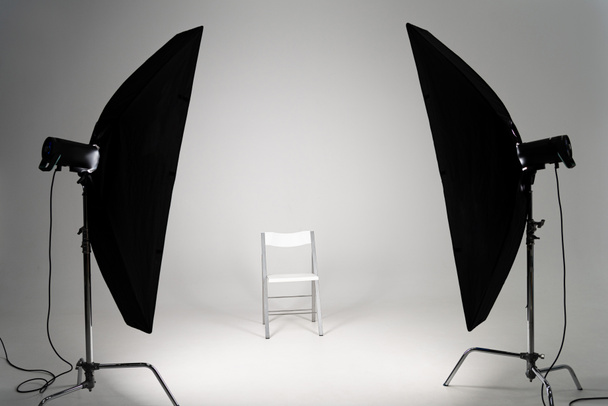 Λευκή καρέκλα με φως στούντιο σε γκρι φόντο - Φωτογραφία, εικόνα