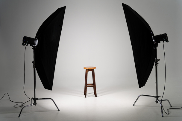 Wooden stool with studio light on grey background - Foto, Bild