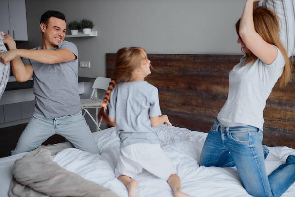 joyful caucasian mom dad and kid fighting playing with pillows - Photo, Image