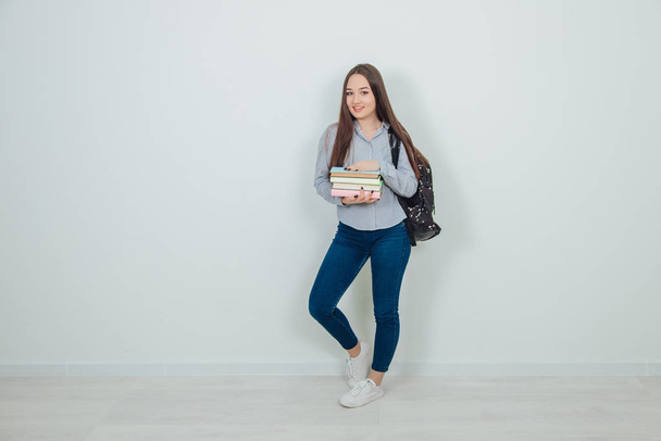 Happy casual asian girl student with backpack standing with stack of books in her hands, posing. - Foto, Bild