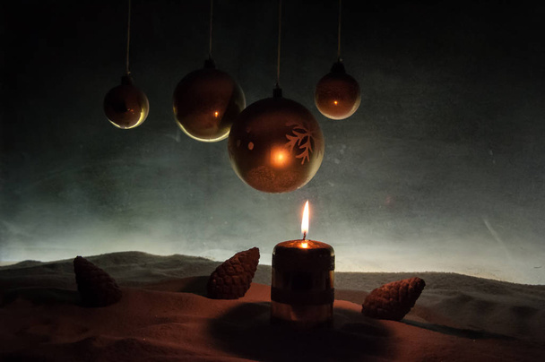 Kreativní umělecká dekorace. Vánoční dekorace s hořícími svíčkami na tmavém pozadí. Vánoční ozdoby přes tmavě zlaté pozadí se světly. - Fotografie, Obrázek
