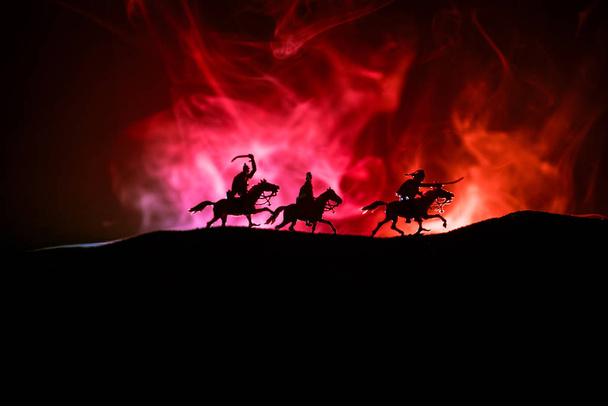 Middeleeuwse slag scène met de cavalerie en infanterie. Silhouetten van figuren als afzonderlijke objecten, strijd tussen krijgers op donker getinte mistige achtergrond. Nachtbeeld. - Foto, afbeelding
