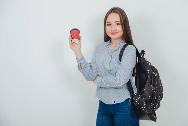 Young beautiful asain student girl standing with a backpack holding a cup of coffee. - Foto, Imagem