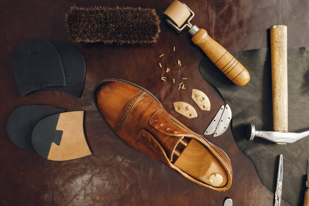 Κατάληψη παπουτσιών, εξοπλισμός επισκευής υποδημάτων. Εργαστήριο υποδηματοποιίας, επισκευασμένες μπότες και εργαλεία bootmaker στο τραπέζι, εργασίες τσαγκάρη - Φωτογραφία, εικόνα