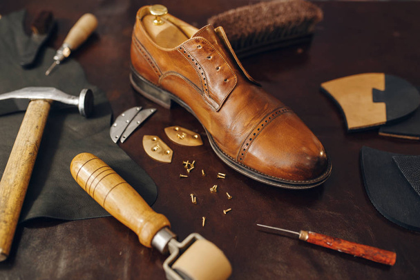 Zaměstnání obuvníka, opravárenské vybavení obuvi. Obuvnická dílna, opravené boty a obuvnické nástroje na stole, ševcovská práce - Fotografie, Obrázek