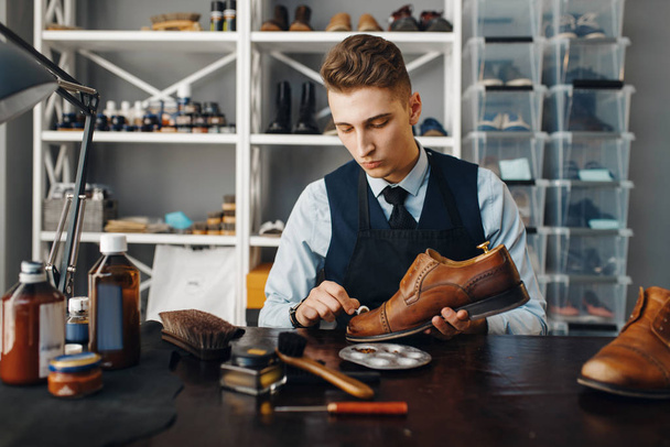 Shoemaker poleruje buty, naprawia obuwie. umiejętności rzemieślnicze, warsztat szewcowy, mistrzowskie prace z butami, szewc - Zdjęcie, obraz