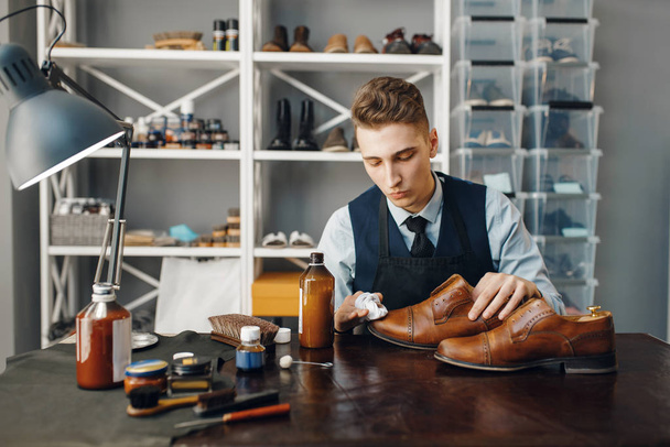 Schoenpoetser poetst de schoen, schoeisel reparatie service. Vakmanschap, schoenmakerij, meesterwerken met laarzen, schoenenwinkel - Foto, afbeelding