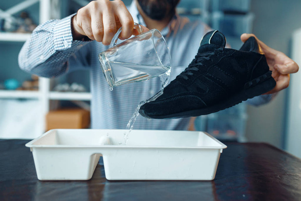 Zapatero comprobar los zapatos para la resistencia al agua, servicio de reparación de calzado. Habilidad artesanal, taller de calzado, obras maestras con botas, zapatería
 - Foto, Imagen