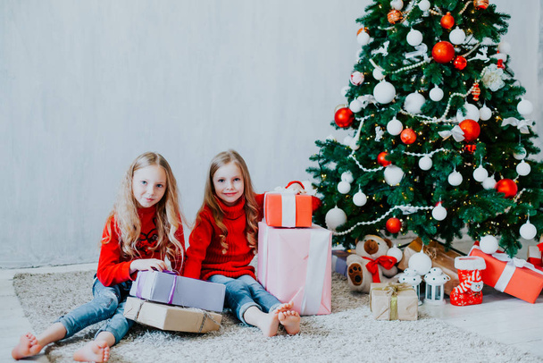 two small girls blonde in red dress at Christmas gifts new year holiday - Zdjęcie, obraz