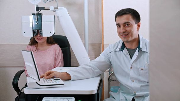 Tratamiento oftalmológico - mujer joven comprobando su agudeza visual con un equipo optometrista - mujer sonriente y el médico
 - Foto, imagen