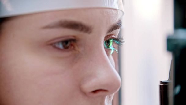 Augenheilkunde - eine junge Frau überprüft ihre Sehschärfe - Überprüfung einer Reaktion auf grünes Licht - Foto, Bild
