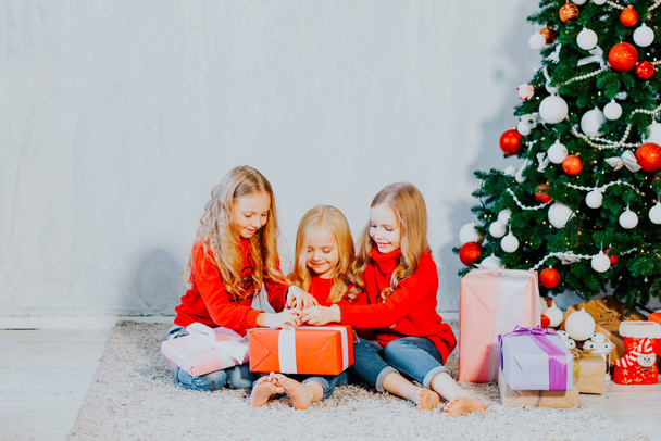 Vacanza di Natale tre ragazza con regali la decorazione dell'albero di nuovo anno su uno sfondo grigio regali
 - Foto, immagini