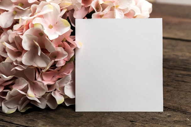 Pastelově růžové hortenzie květiny a kus papíru na dřevěné podložce - Fotografie, Obrázek