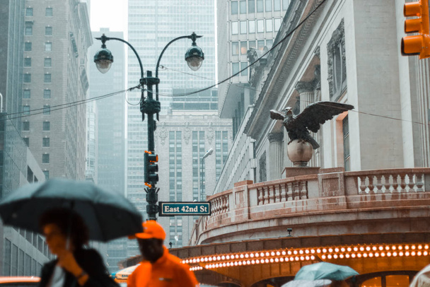 Нью-Йорк, США - 16 июня 2017 года: Центр Нью-Йорка в дождливый день. Восточный 42-й штрет, шт. Нью-Йорк - люди бегут под дождем при облачной, грозовой погоде
 - Фото, изображение