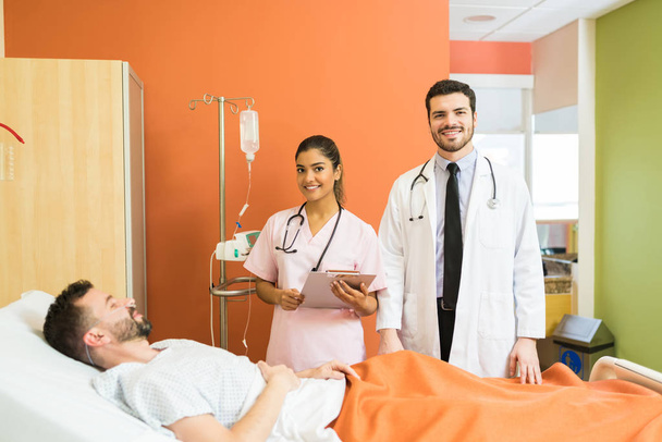 Magabiztos mosolygó orvosok állnak beteg betegek mellett a kórházban. - Fotó, kép