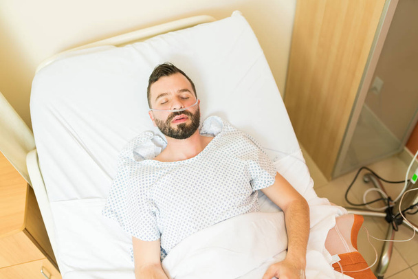 Directamente encima de la inyección de paciente inconsciente acostado en la cama en el hospital
 - Foto, Imagen