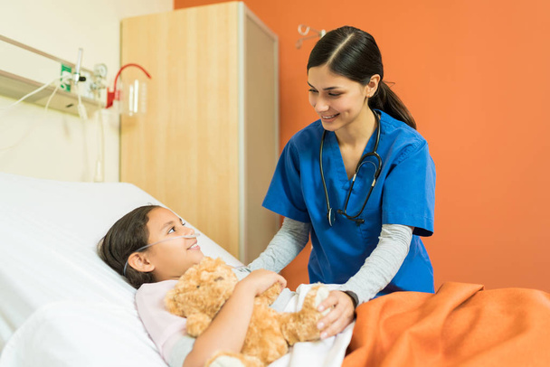 Infermiera che parla con un piccolo paziente al letto d'ospedale durante il trattamento
 - Foto, immagini