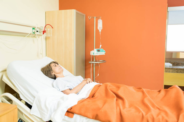 Patiente âgée réfléchie avec perfusion intraveineuse couchée sur le lit à l'hôpital pendant le traitement
 - Photo, image