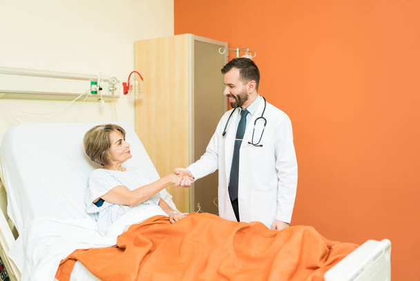 Médico adulto médio apertando as mãos com o paciente sênior que sofre de problema respiratório no hospital
 - Foto, Imagem