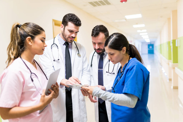 Medici e infermieri che guardano i rapporti medici mentre discutono in corridoio in ospedale
 - Foto, immagini