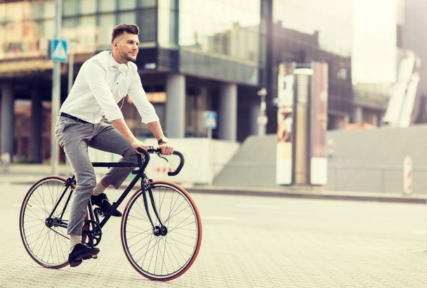 man with headphones riding bicycle on city street - Foto, Imagen