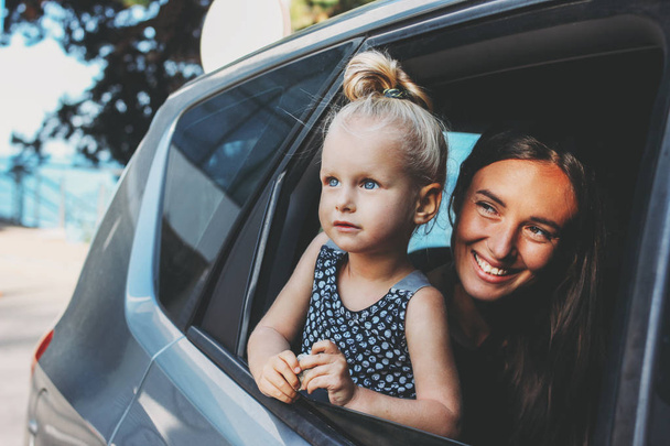 Pequena menina bebê criança olha para fora da janela do carro com sua mãe
 - Foto, Imagem