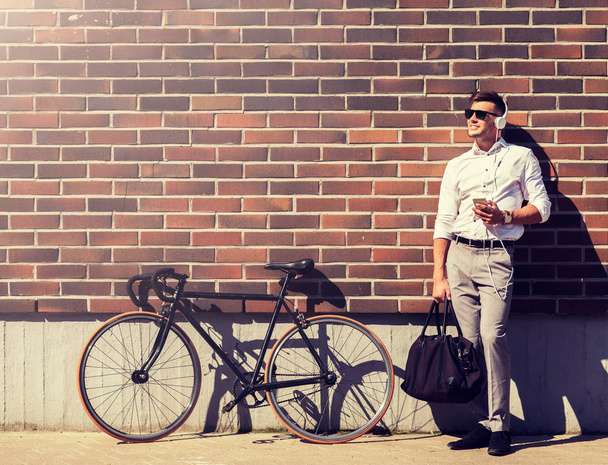 man with headphones, smartphone and bicycle - Фото, изображение