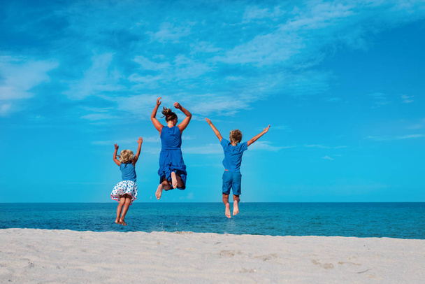 family enjoy beach, mother with kids jump on vacation at sea - Fotó, kép